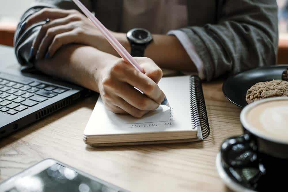 A business owner writing out a plan in a spiral notebook