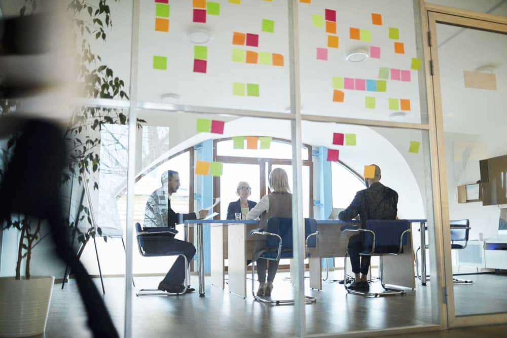 A group of employees in a meeting with post-it notes on the walls