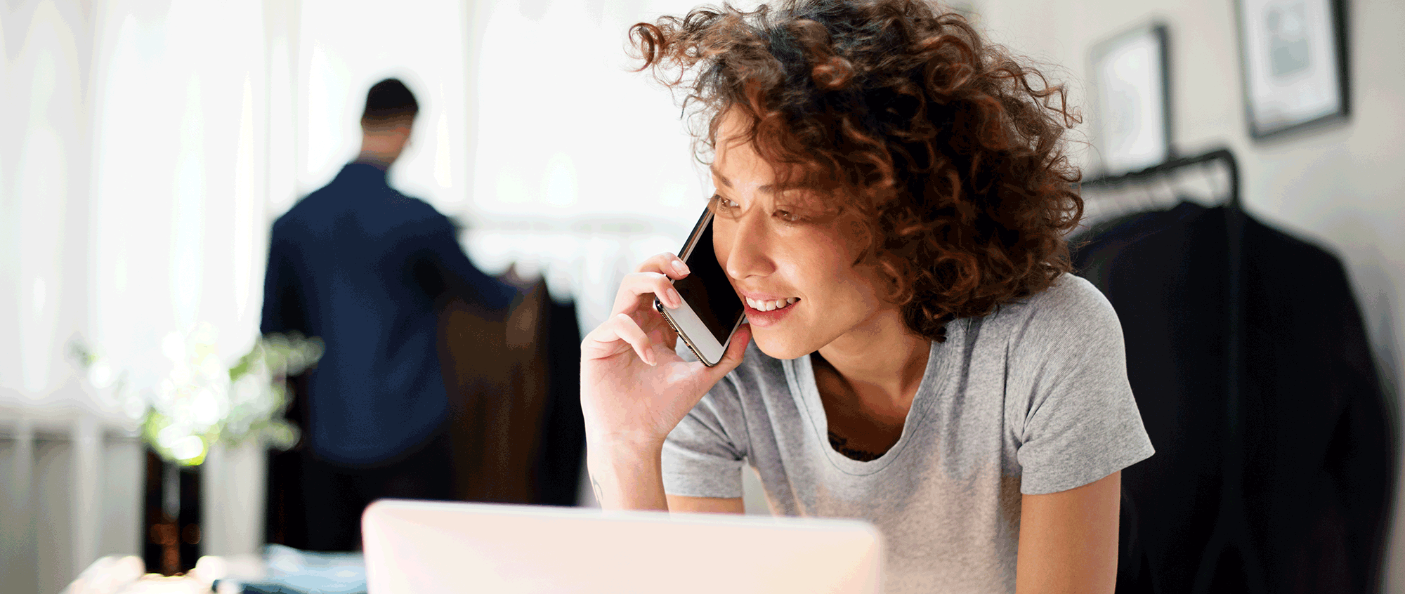 woman business owner on her laptop, taking a call at her desk