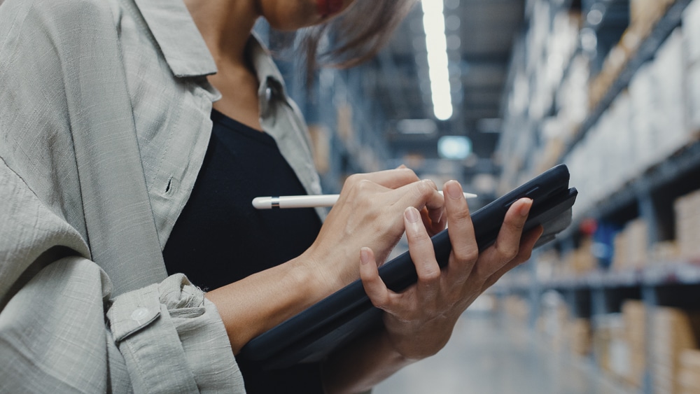 Manager uses an iPad to calculate inventory for in retail shopping center. Distribution, Logistics, Packages ready for shipment.